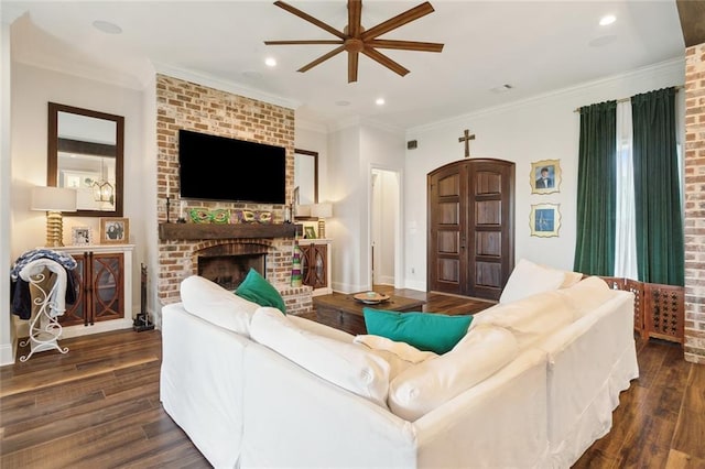 living room featuring crown molding, dark wood-type flooring, ceiling fan, and a fireplace