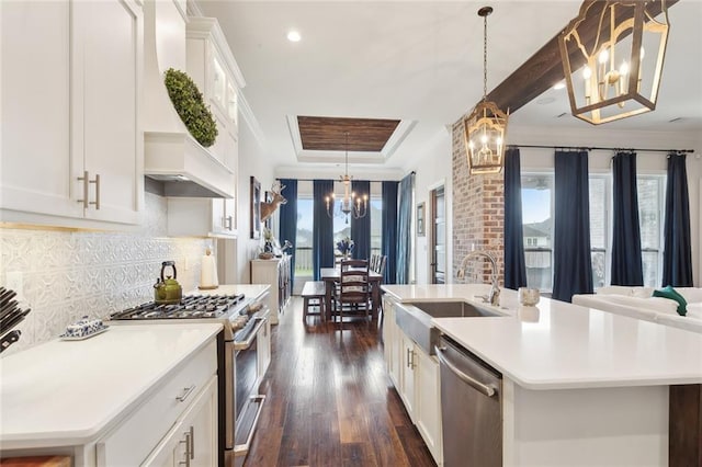 kitchen featuring a kitchen island with sink, a notable chandelier, decorative light fixtures, and appliances with stainless steel finishes