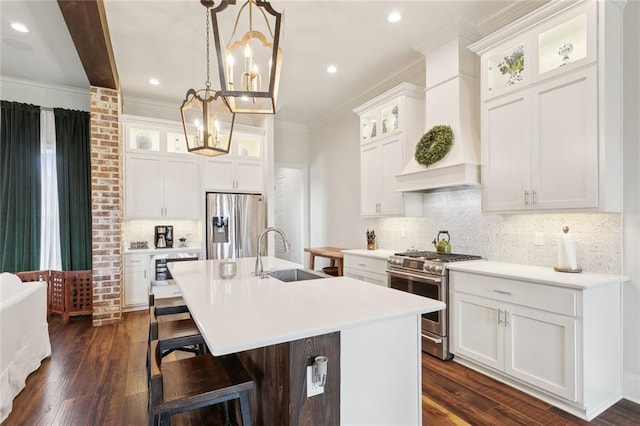 kitchen featuring sink, appliances with stainless steel finishes, a kitchen island with sink, white cabinetry, and decorative light fixtures