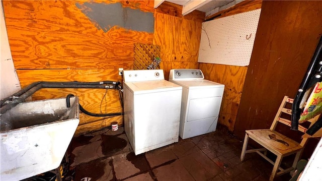 laundry room featuring sink, washing machine and dryer, and wood walls