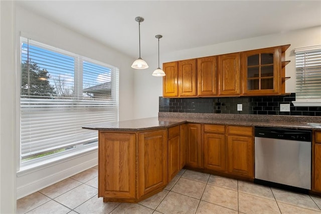 kitchen with light tile patterned floors, decorative backsplash, decorative light fixtures, stainless steel dishwasher, and kitchen peninsula