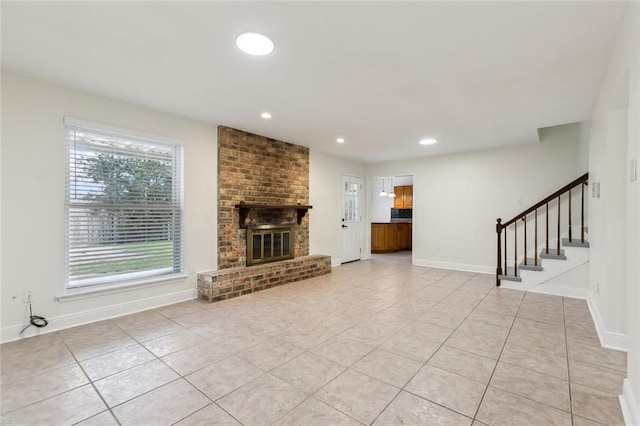 unfurnished living room with light tile patterned flooring and a brick fireplace