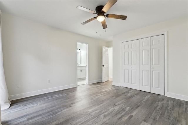 unfurnished bedroom featuring dark wood-type flooring, ceiling fan, ensuite bathroom, and a closet