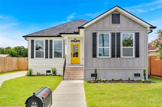 view of front of property with a front lawn, crawl space, board and batten siding, and fence