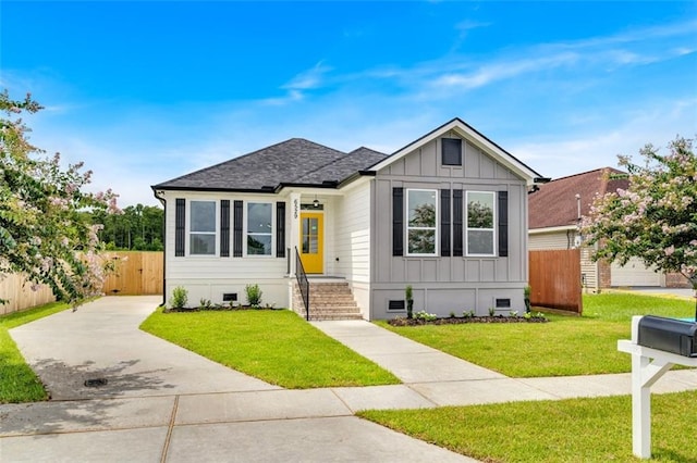 view of front of house with a shingled roof, fence, crawl space, board and batten siding, and a front yard