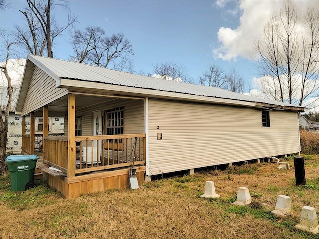 view of side of property featuring a porch and metal roof