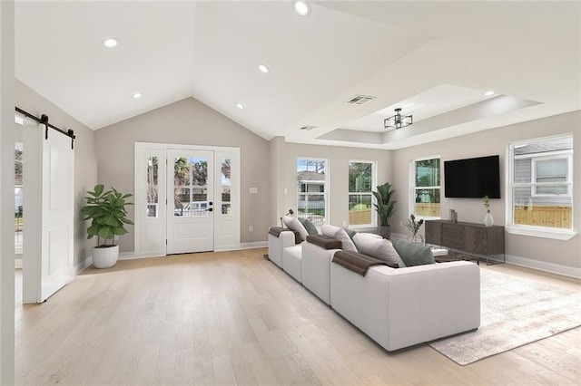 living room featuring vaulted ceiling, a barn door, and light wood-type flooring