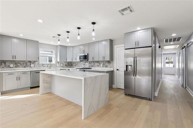 kitchen with light hardwood / wood-style floors, decorative light fixtures, stainless steel appliances, and a center island