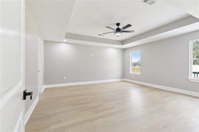 unfurnished room with light hardwood / wood-style floors, a raised ceiling, and ceiling fan