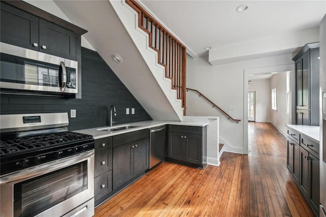 kitchen with sink, backsplash, stainless steel appliances, and light hardwood / wood-style floors