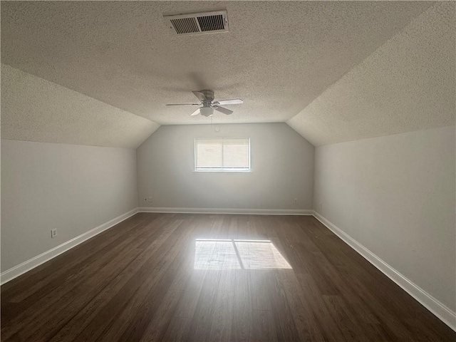 additional living space featuring ceiling fan, lofted ceiling, dark hardwood / wood-style flooring, and a textured ceiling