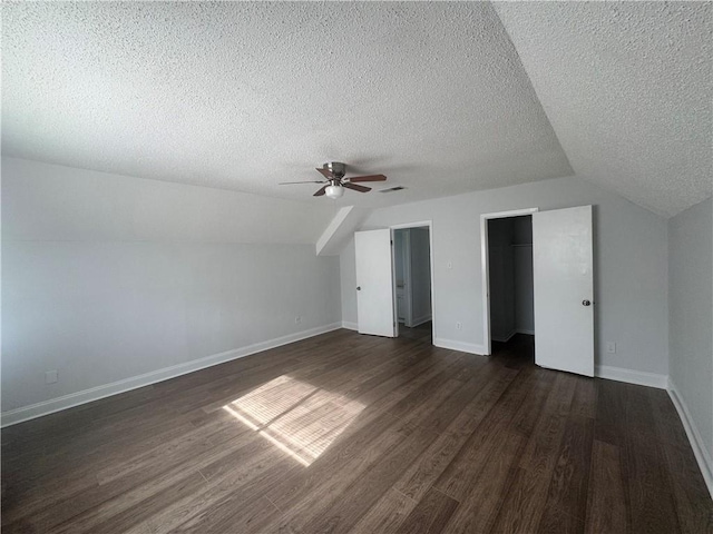 additional living space with ceiling fan, lofted ceiling, a textured ceiling, and dark hardwood / wood-style flooring