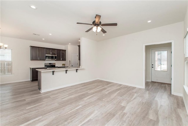 kitchen featuring dark brown cabinetry, a wealth of natural light, stainless steel appliances, and a kitchen bar