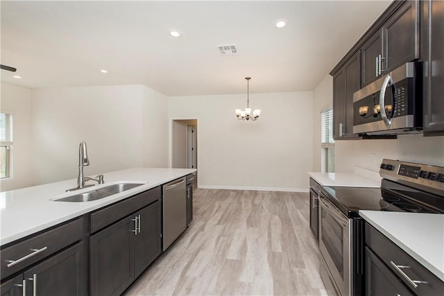 kitchen with sink, appliances with stainless steel finishes, an inviting chandelier, decorative light fixtures, and light wood-type flooring