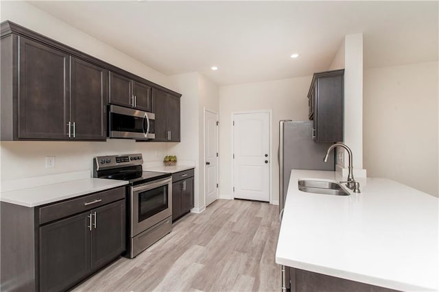 kitchen featuring sink, dark brown cabinets, light hardwood / wood-style flooring, and appliances with stainless steel finishes