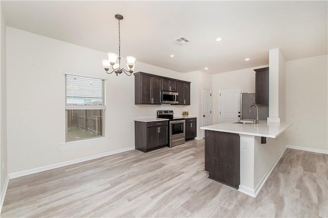 kitchen featuring light hardwood / wood-style flooring, appliances with stainless steel finishes, hanging light fixtures, a kitchen bar, and kitchen peninsula