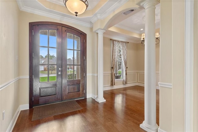 foyer entrance featuring dark hardwood / wood-style flooring, crown molding, decorative columns, and french doors