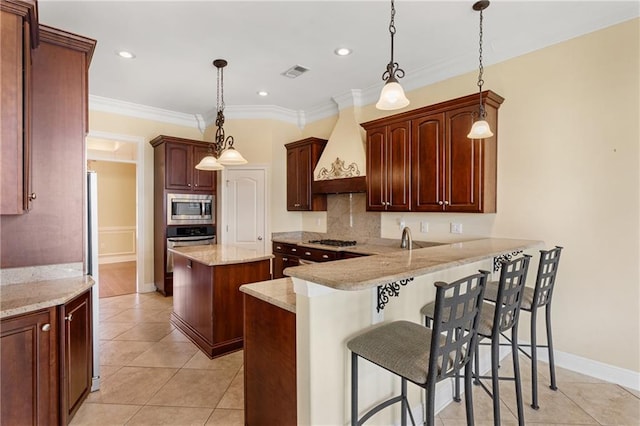 kitchen with appliances with stainless steel finishes, a kitchen breakfast bar, custom range hood, decorative light fixtures, and kitchen peninsula