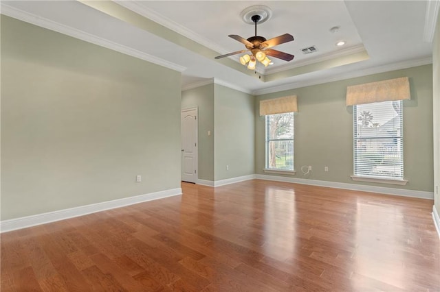 empty room featuring crown molding, ceiling fan, light hardwood / wood-style floors, and a tray ceiling