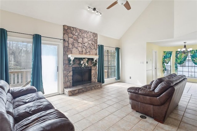 living room featuring ceiling fan with notable chandelier, a fireplace, high vaulted ceiling, and light tile patterned flooring