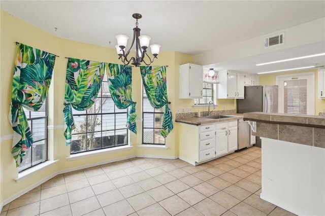 kitchen with pendant lighting, sink, stainless steel appliances, white cabinets, and light tile patterned flooring