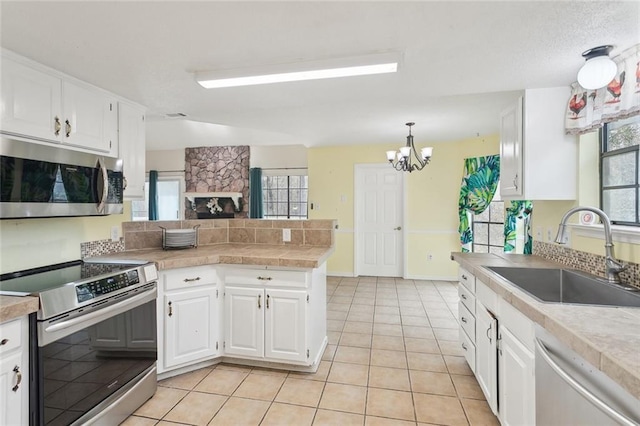 kitchen with pendant lighting, sink, stainless steel appliances, a healthy amount of sunlight, and white cabinets