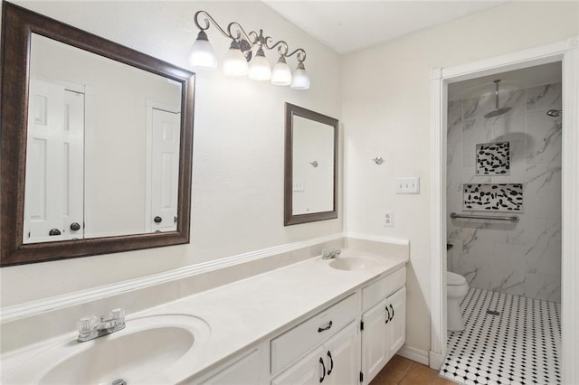 bathroom with tiled shower, vanity, toilet, and tile patterned floors