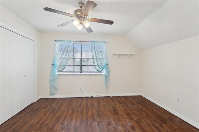 unfurnished bedroom featuring dark hardwood / wood-style floors, vaulted ceiling, a closet, and ceiling fan