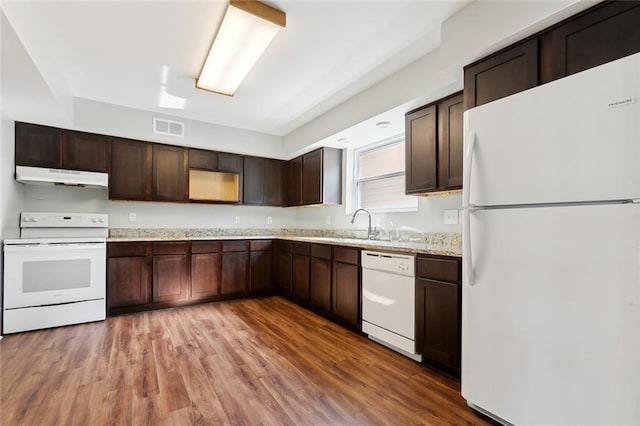 kitchen featuring dark brown cabinetry, sink, wood-type flooring, white appliances, and light stone countertops