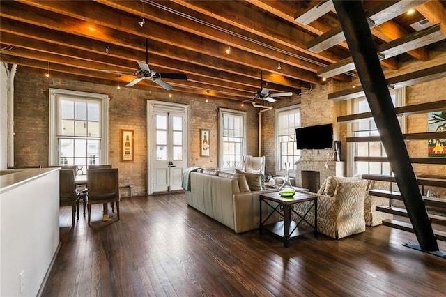 living room featuring ceiling fan, a fireplace, brick wall, dark hardwood / wood-style flooring, and beamed ceiling