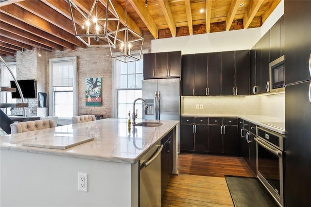 kitchen featuring sink, hardwood / wood-style flooring, pendant lighting, stainless steel appliances, and a kitchen island with sink