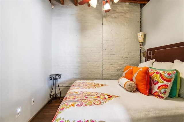 bedroom featuring dark hardwood / wood-style floors and brick wall