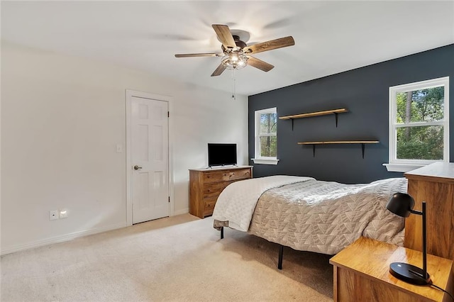 bedroom featuring a ceiling fan, multiple windows, light colored carpet, and baseboards