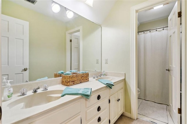 full bath featuring visible vents, toilet, double vanity, and a sink