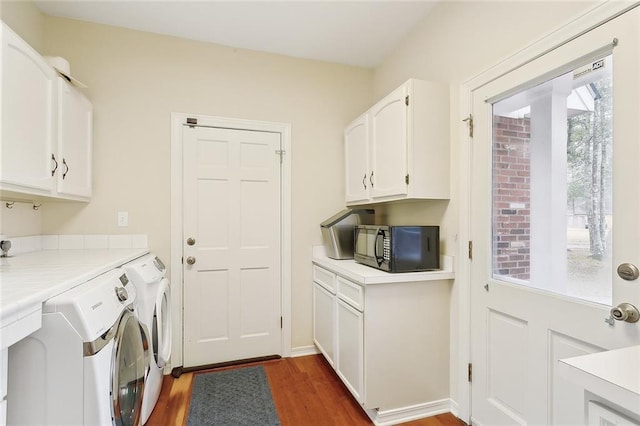 laundry room featuring washing machine and dryer, cabinet space, and wood finished floors