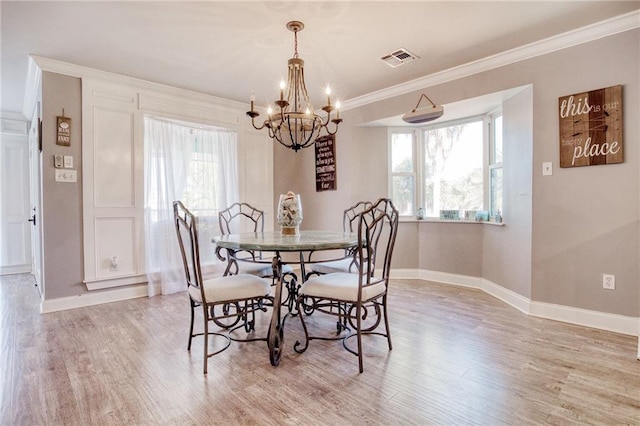 dining space featuring crown molding, a healthy amount of sunlight, light hardwood / wood-style flooring, and a notable chandelier