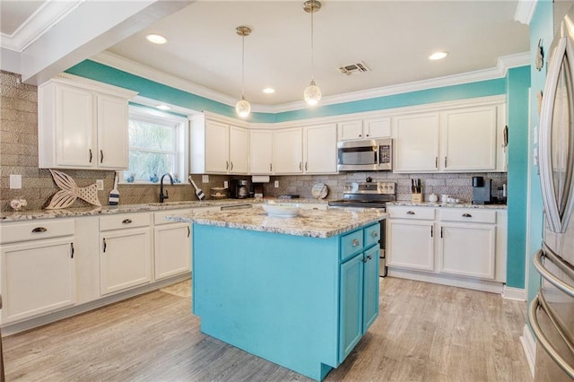 kitchen with sink, light stone counters, hanging light fixtures, appliances with stainless steel finishes, and a kitchen island