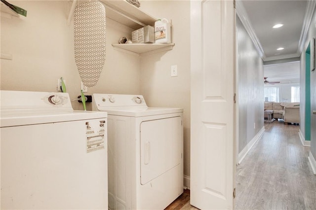 laundry room with crown molding, washing machine and clothes dryer, and light hardwood / wood-style flooring