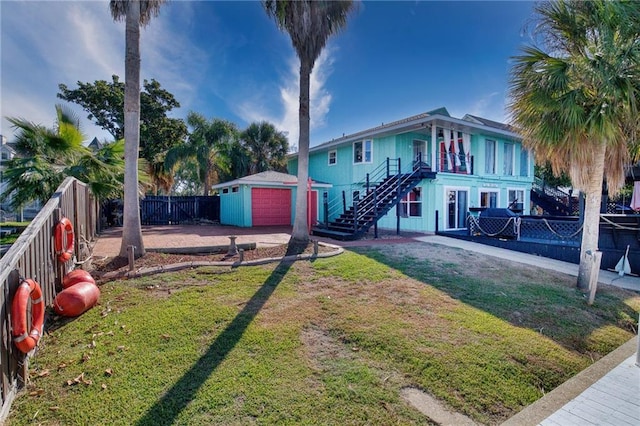 view of front of property with a garage, an outdoor structure, and a front lawn