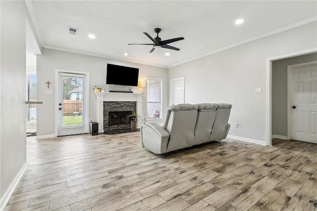 living room featuring a premium fireplace, crown molding, ceiling fan, and light hardwood / wood-style floors