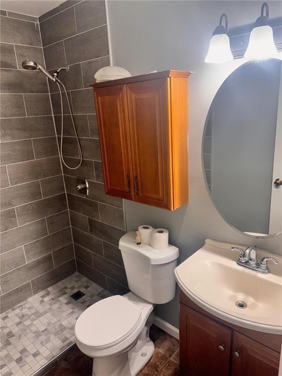 bathroom with a tile shower, vanity, and toilet