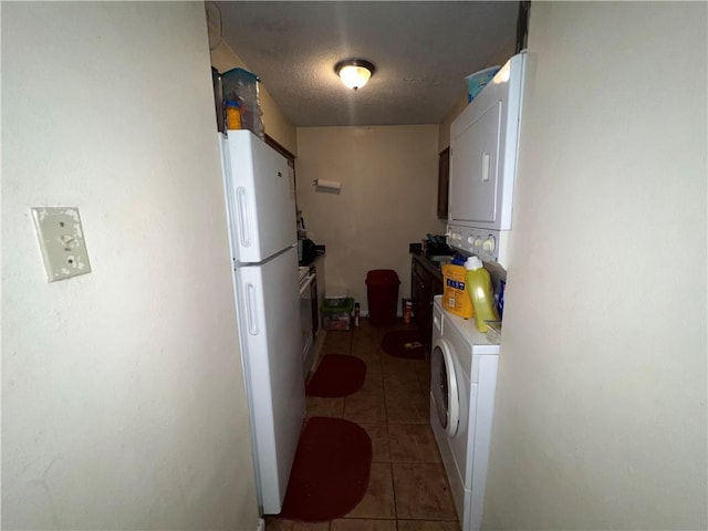 332022 Kabel Dr, New Orleans, LA 70131 - kitchen featuring freestanding refrigerator, stacked washer / drying machine, light tile patterned floors, white cabinetry, and light countertops