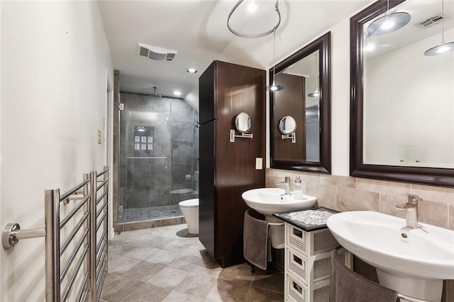 bathroom featuring a shower with shower door, sink, tile walls, and toilet