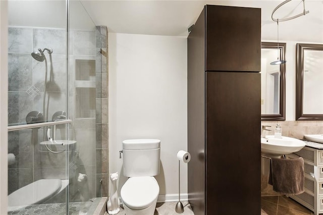 bathroom with tile patterned flooring, walk in shower, sink, and toilet