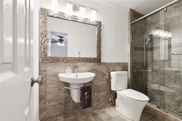 bathroom featuring crown molding, a shower with door, ceiling fan, tile walls, and toilet