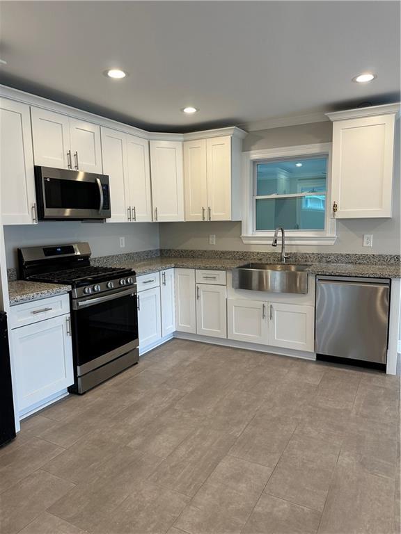 kitchen with white cabinetry, sink, stainless steel appliances, and stone countertops