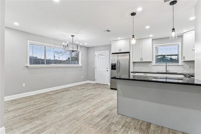 kitchen featuring pendant lighting, sink, white cabinetry, stainless steel refrigerator with ice dispenser, and decorative backsplash