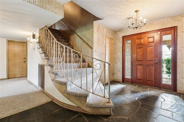 entrance foyer featuring carpet floors, a textured ceiling, and an inviting chandelier