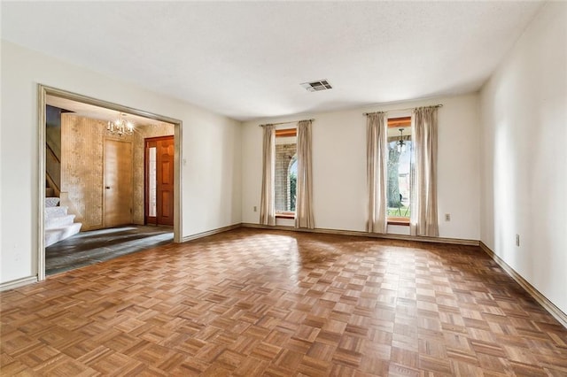 empty room featuring an inviting chandelier and light parquet flooring