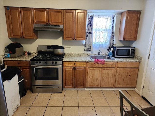 kitchen featuring light stone counters, sink, light tile patterned flooring, and appliances with stainless steel finishes